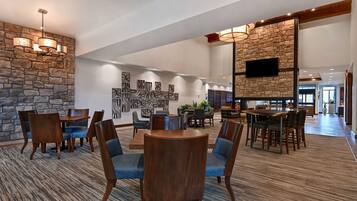 A spacious lobby with a stone wall, a fireplace, and a flat-screen TV mounted on the wall.