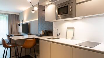 A modern kitchen with a central island, bar stools, a microwave, and a flat-screen TV.