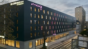 Een modern hotel met een neonreclame, meerdere ramen en een goed verlichte gevel.