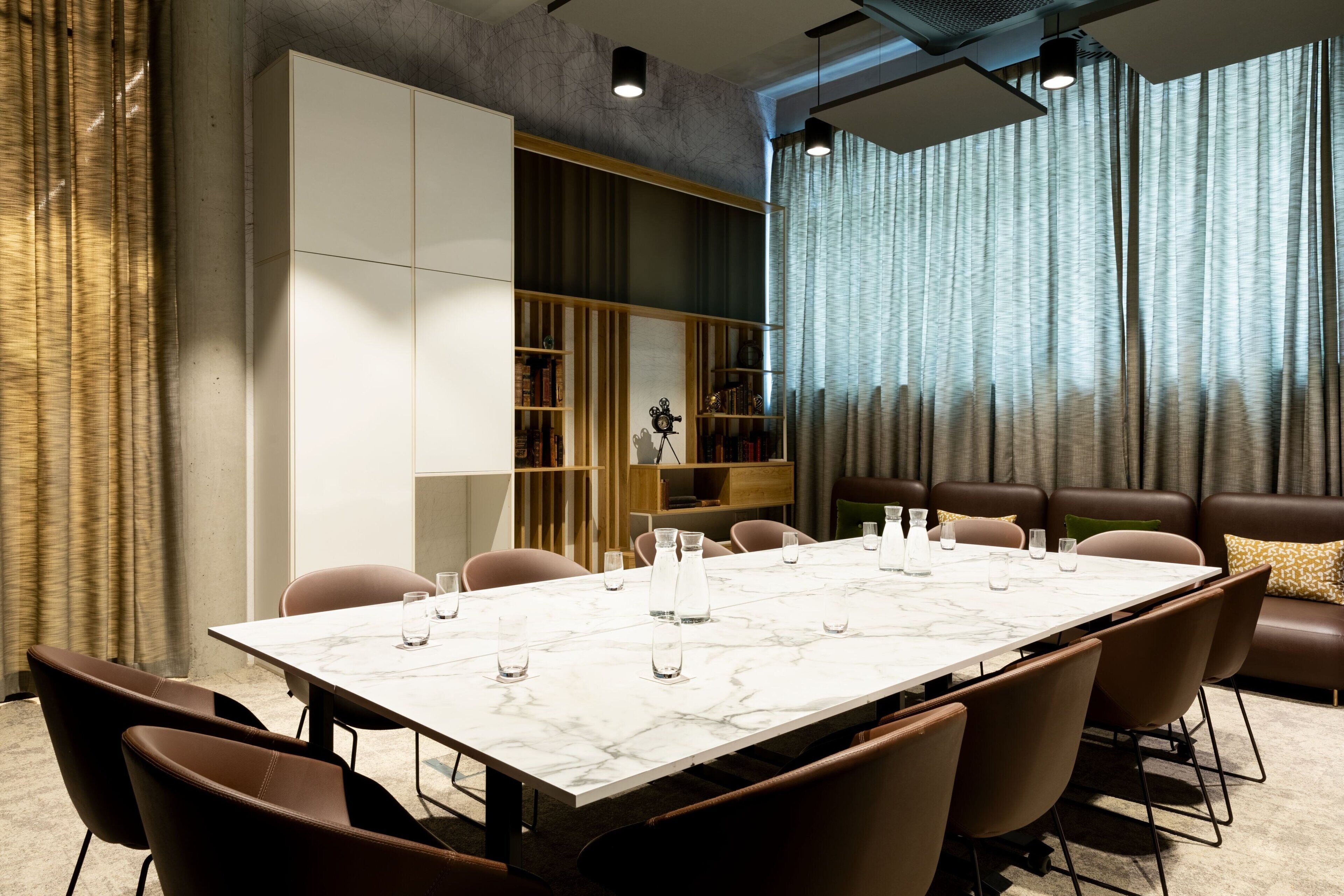 Une salle de conférence moderne, dotée d’une table en marbre, de fauteuils en cuir, d’une bibliothèque et d’un canapé.