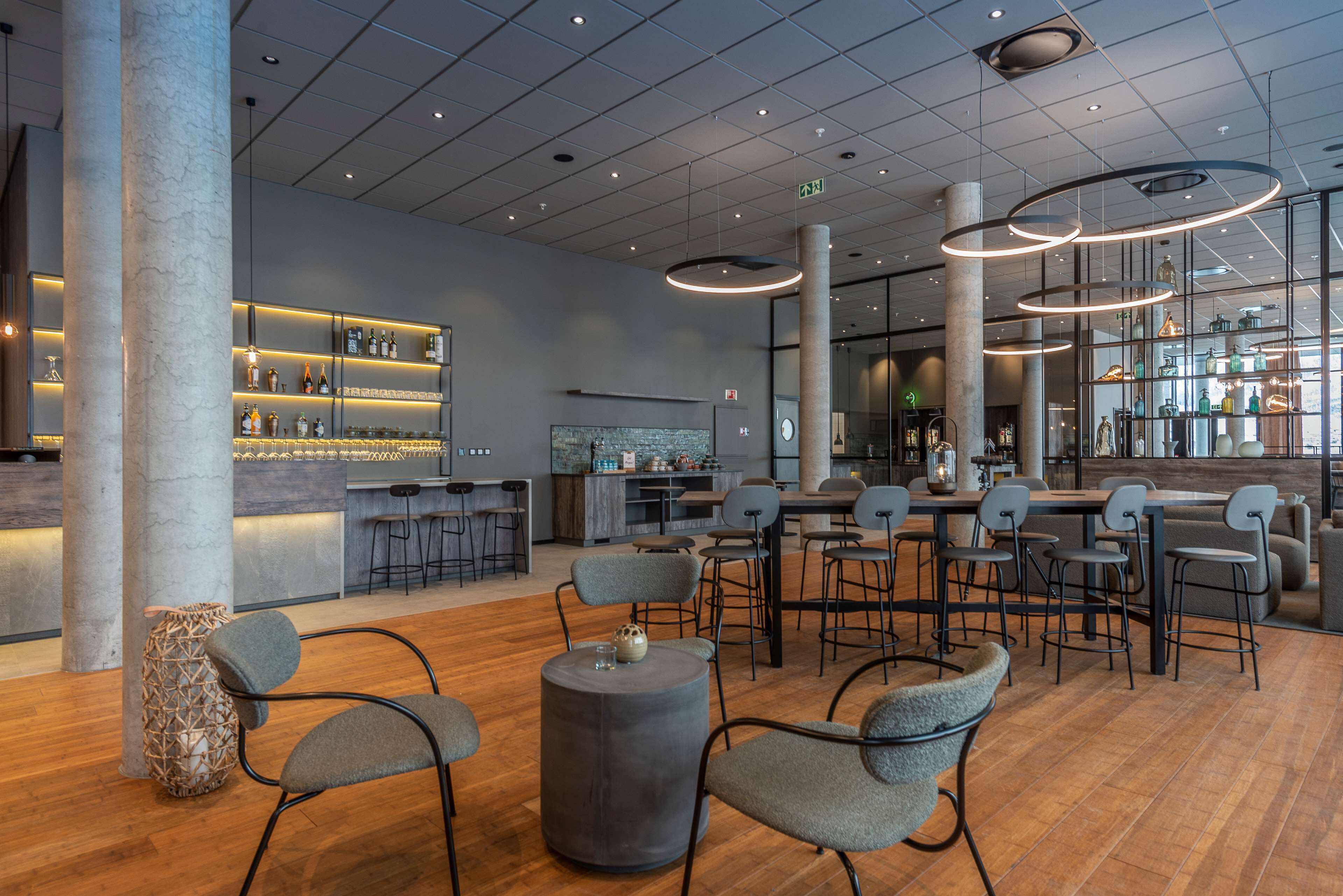 A modern bar area with seating, a bar counter, and a large window.