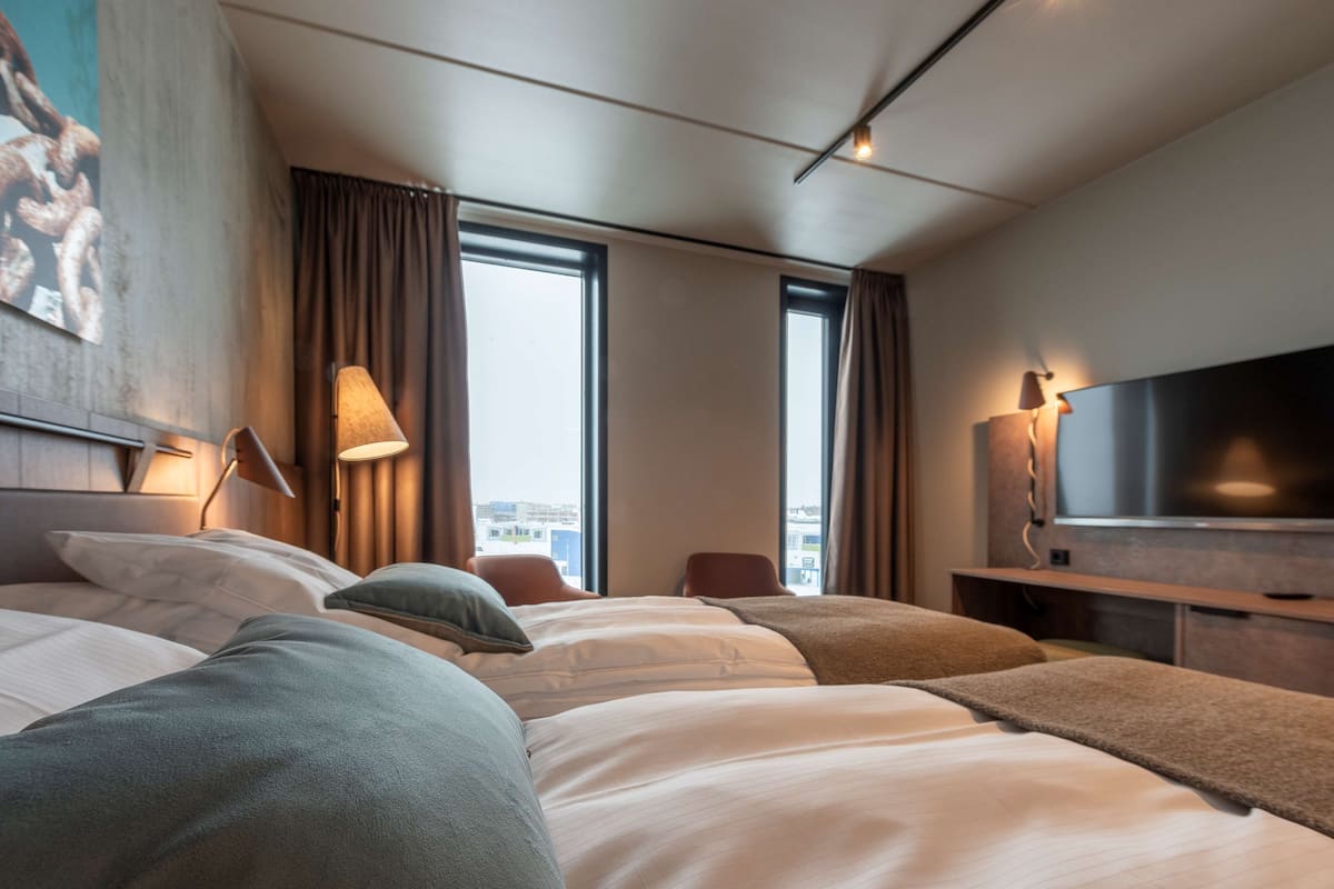 A hotel room with a large bed, a TV, and a city view.