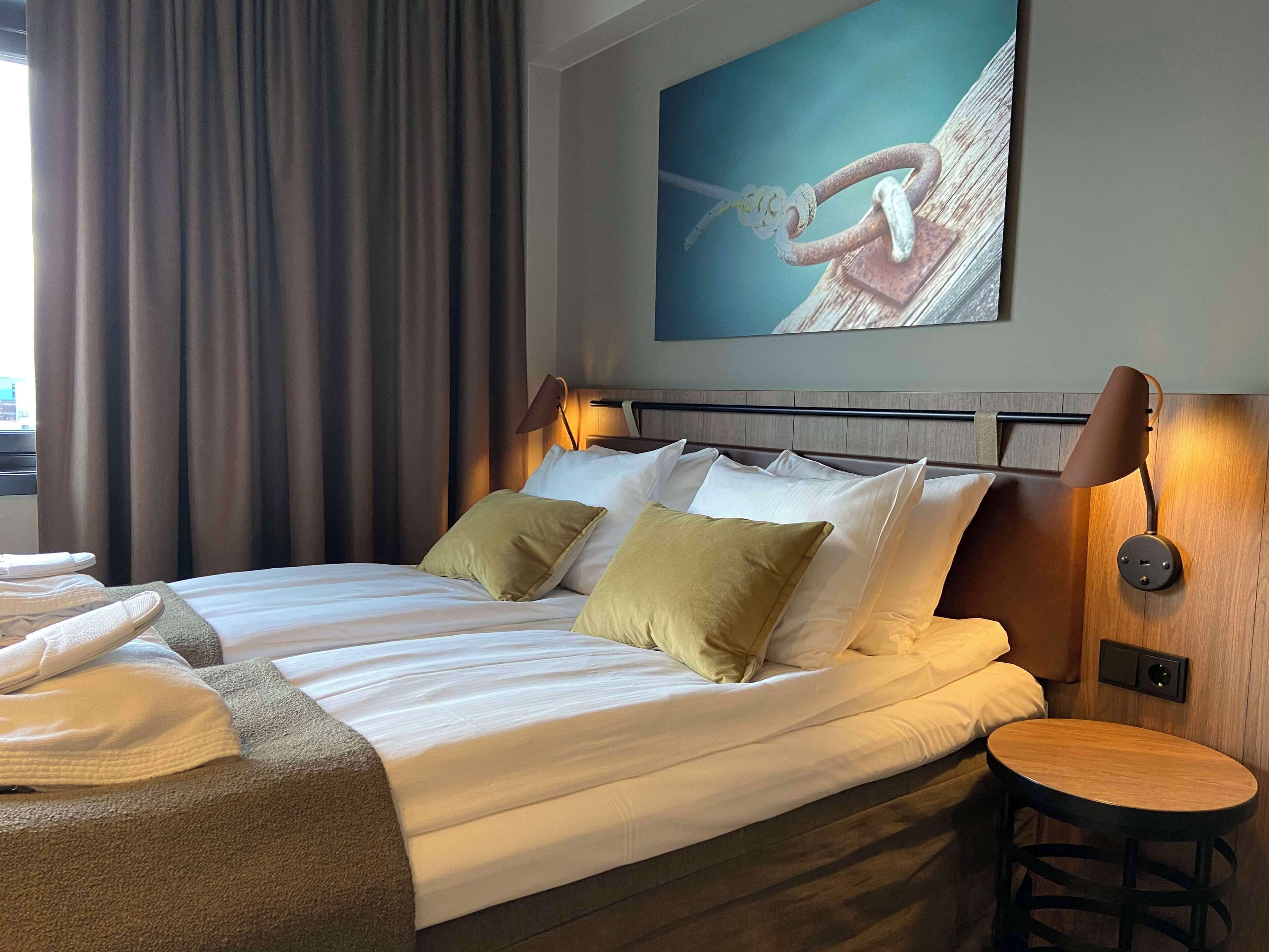 Una habitación de hotel con una cama bien hecha, una mesa redonda de madera y un cuadro en la pared.