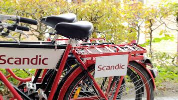 Una bicicleta roja con la marca 'Scandic', equipada con una canasta y un asiento.