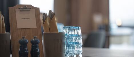 A table with a "Reserved Table" sign, utensils, salt and pepper shakers, and a water bottle.