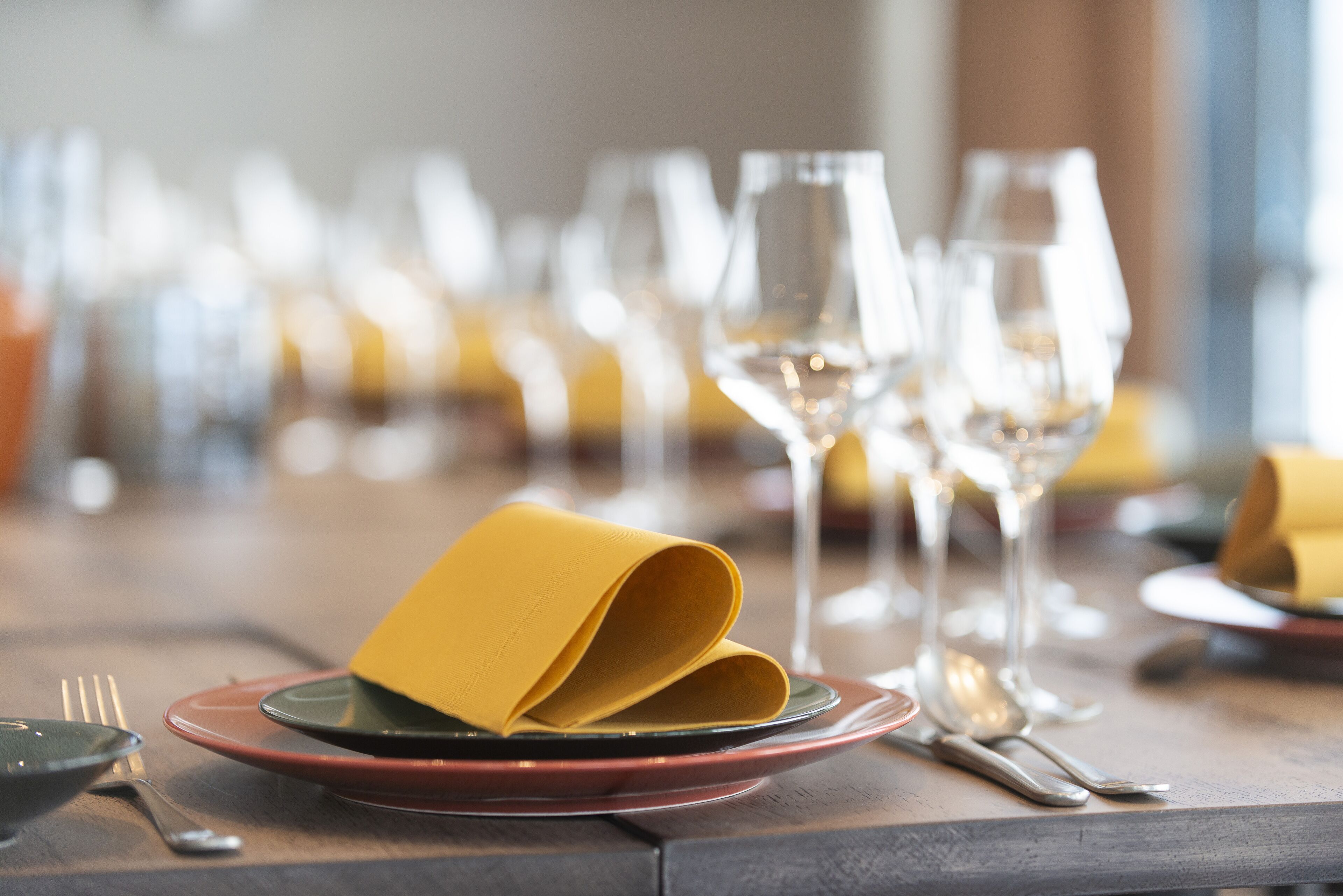 Una mesa de comedor servida con platos, cubiertos y vasos.