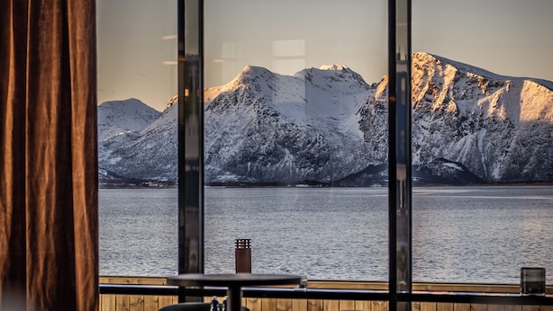 Un restaurant offrant une vue sur des montagnes enneigées et un plan d’eau.