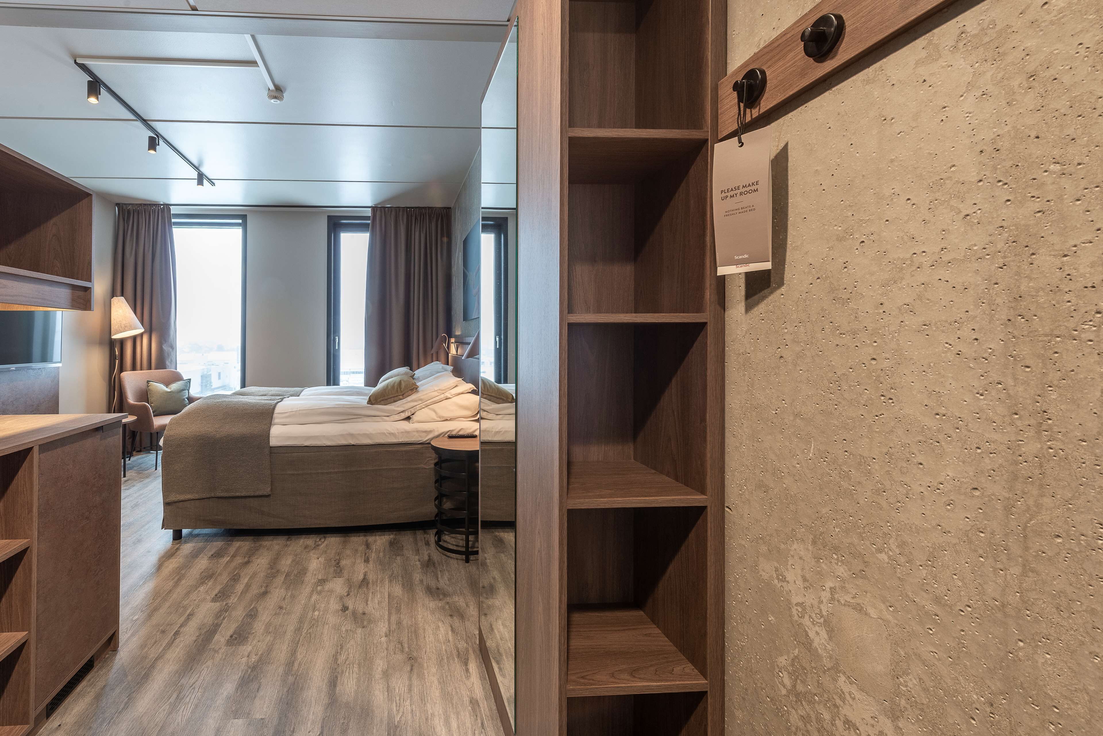 A modern hotel room with a bed, a desk, and a large window.