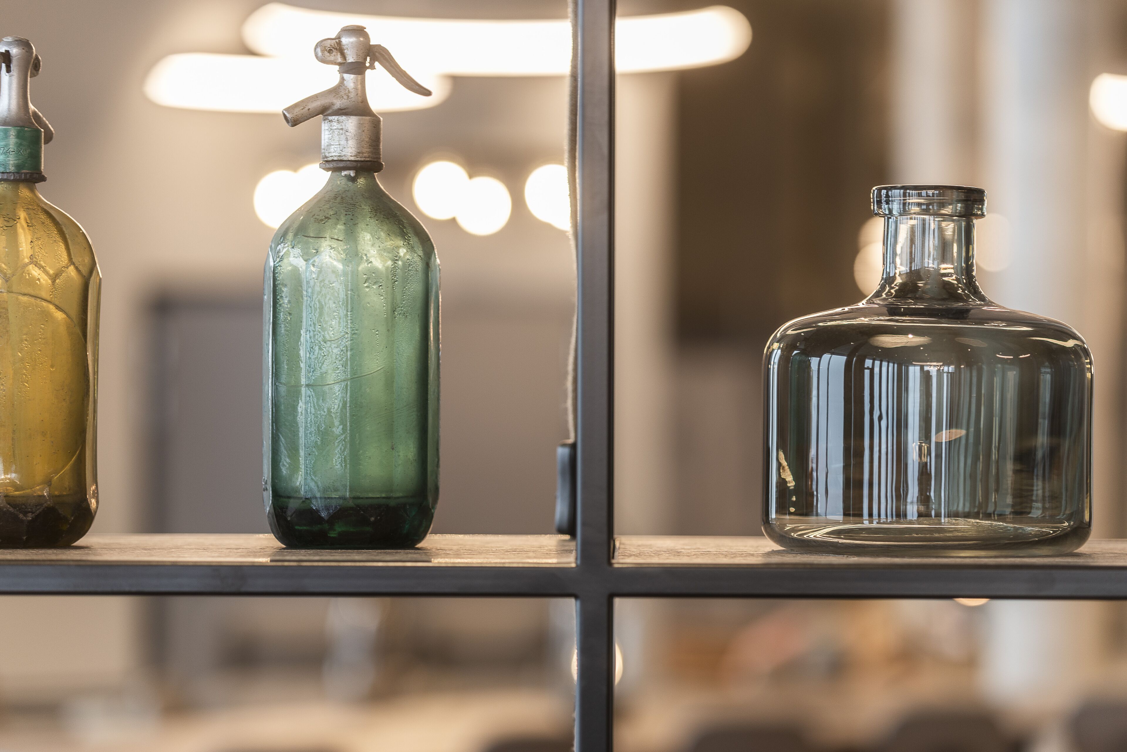 Trois bouteilles en verre sur une étagère.
