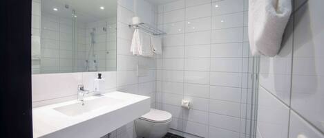 A modern bathroom with a white sink, toilet, and glass shower enclosure.