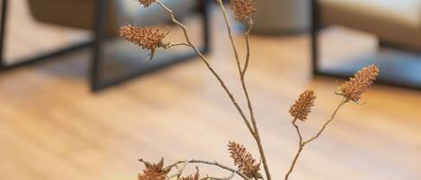 A modern interior with a clear glass vase containing dried branches on a wooden table.