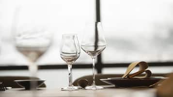 Two wine glasses on a table with a window in the background.