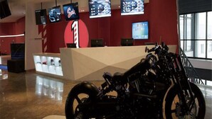 A motorcycle in a modern indoor setting with multiple screens displaying content.