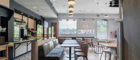 Un restaurante moderno con zona de bar, mesas y un amplio ventanal con vistas.