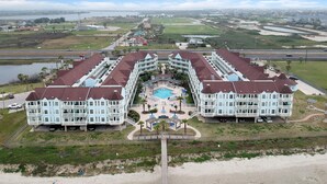A large resort with a central pool, multiple guest buildings, and a view of the surrounding landscape. - Seascape 2107 1 Bedroom Condo by RedAwning (Galveston)