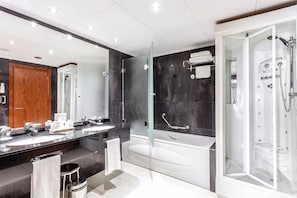 Un baño moderno con un espejo grande, dos lavamanos, una bañera y ducha a ras de suelo.