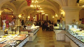 Un área de bufé con varias estaciones de comida y mucha gente.