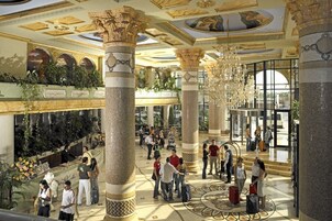 Un vestíbulo amplio con techos altos, columnas ornamentales y un candelabro central.