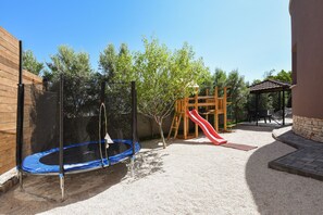 A backyard with a trampoline, a slide, and a wooden play structure.