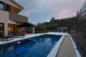 Une maison moderne dotée d’une piscine, d’un espace extérieur aménagé et d’une clôture en bois.