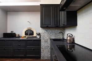 A modern kitchen with dark cabinetry, a black countertop, and a tiled backsplash.