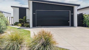 A modern two-story building with a large garage door, surrounded by well-maintained landscaping and a paved driveway.