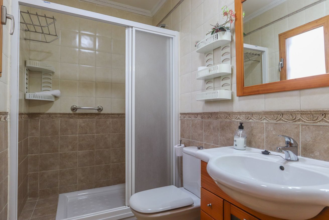 A bathroom with a shower, toilet, sink, and mirror.