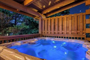 A hot tub with a wooden deck and a night sky view.