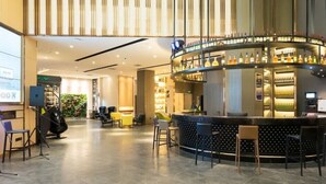 A modern bar area with a curved counter, bar stools, and a projection screen displaying text. - Starway Hotel (Shunyi)
