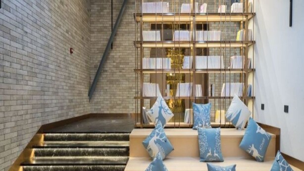 A staircase leading to a seating area with a bookshelf. - Starway Hotel (Shunyi)