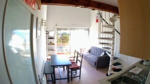 A room with a dining table, chairs, a sofa, a staircase, and a kitchen area. - T2 Duplex with view, Garage, Balcony, Wifi (Font-Romeu-Odeillo-Via)