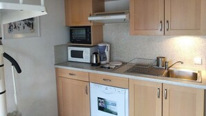 A compact kitchen with wooden cabinets, a microwave, a coffee maker, and a dishwasher. - T2 Duplex with view, Garage, Balcony, Wifi (Font-Romeu-Odeillo-Via)
