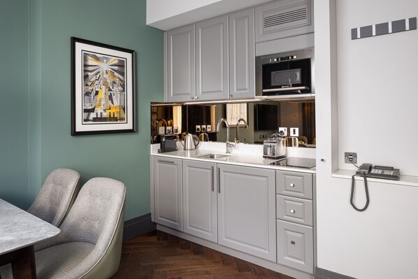 A modern kitchen with grey cabinets, a microwave, and a coffee maker. There is a framed picture on the wall and a telephone on the counter. - Hapimag Apartments London (London)