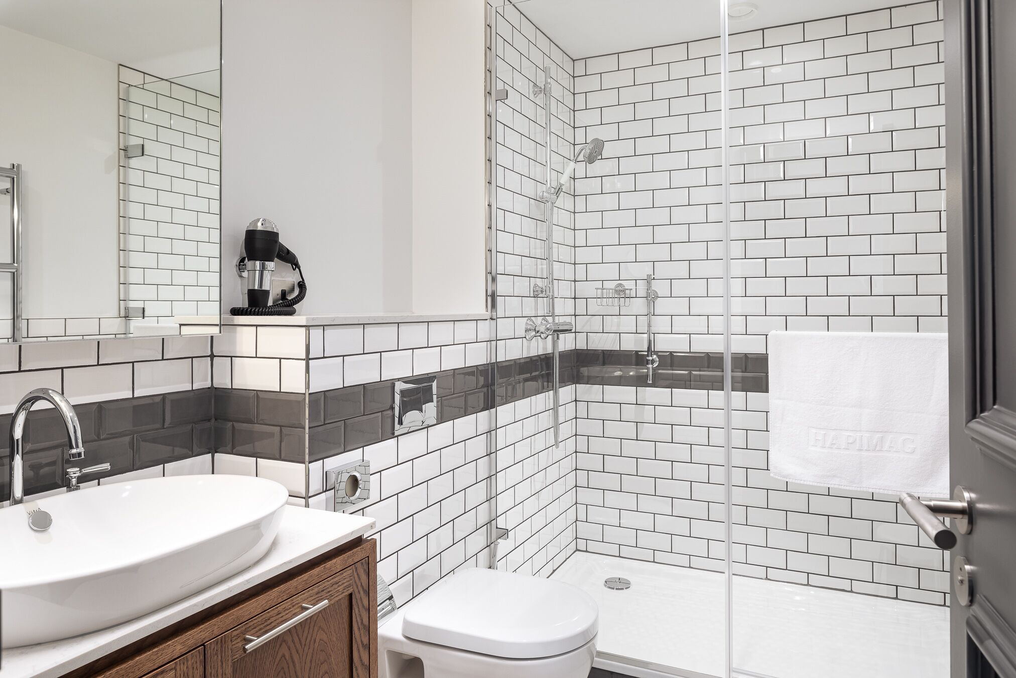 A modern bathroom with a white sink, a toilet, and a glass-enclosed shower area.
