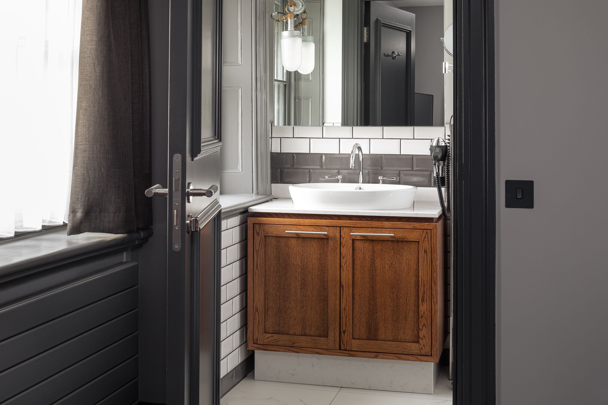 A bathroom with a white sink, wooden cabinets, a mirror, and a towel rack.