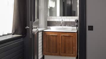 A bathroom with a white sink, wooden cabinets, a mirror, and a towel rack.