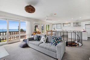 A modern living room with a grey sofa, a dining area with a round table, and a kitchen with white cabinets. - 1 Luana (Lorne)