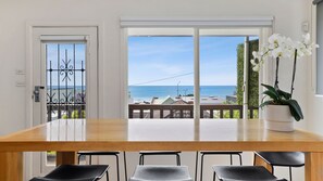 Enjoy meals with a view of the ocean from this dining area, featuring a large table and comfortable seating for four.