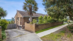 Stunning two-story home with a pitched roof, paved driveway, and a beautiful sea view.
