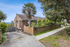 A two-story brick house with a tiled roof, a paved driveway, and a wooden fence.