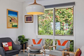Ein Zimmer mit einem großen Fenster, einem Gemälde und zwei Sessel mit Kissen.