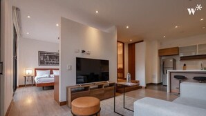 A modern hotel room with a large flat-screen TV, a comfortable bed, a seating area with a coffee table, and a kitchenette. - w* | Artistic Loft in Parque Virrey (Bogotá)