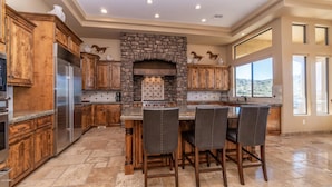 A spacious kitchen with wooden cabinets, a stone fireplace, and a large dining area with four chairs.