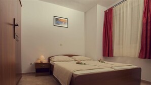 Een slaapkamer met een bed, nachtkastje, lamp en een foto aan de muur.