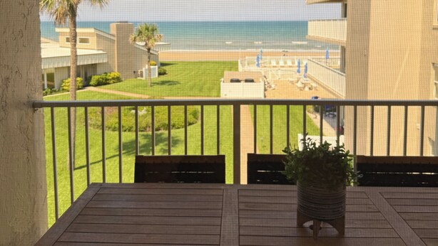 Een balkon met uitzicht op een strand en een zwembad.