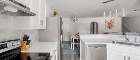 A modern kitchen with white cabinetry, a stainless steel refrigerator, a built-in oven, and a dishwasher.