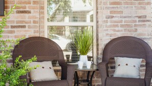 Eine Terrasse mit zwei Korbstühlen, einem kleinen Tisch und einem Blumentopf.