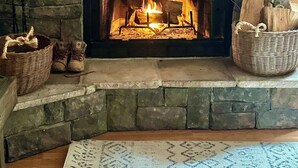 A stone fireplace with a fire, a wooden mantel, and a sign above it.
