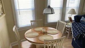 A dining area with a round wooden table, white chairs, and a hanging lamp. - Peace and quiet within short walking distance to the beach.  (Ocean City)