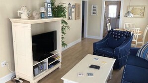 A living room with a television, a coffee table, and a blue sofa. - Peace and quiet within short walking distance to the beach.  (Ocean City)